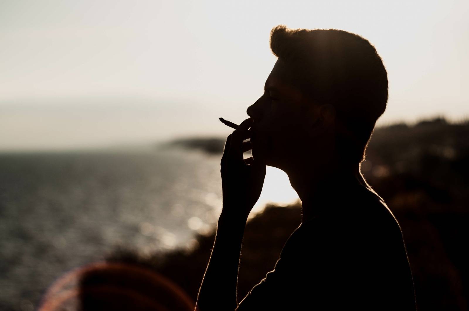 Young man smoking cannabis on the sea background at 420 spot. SpeedGreens