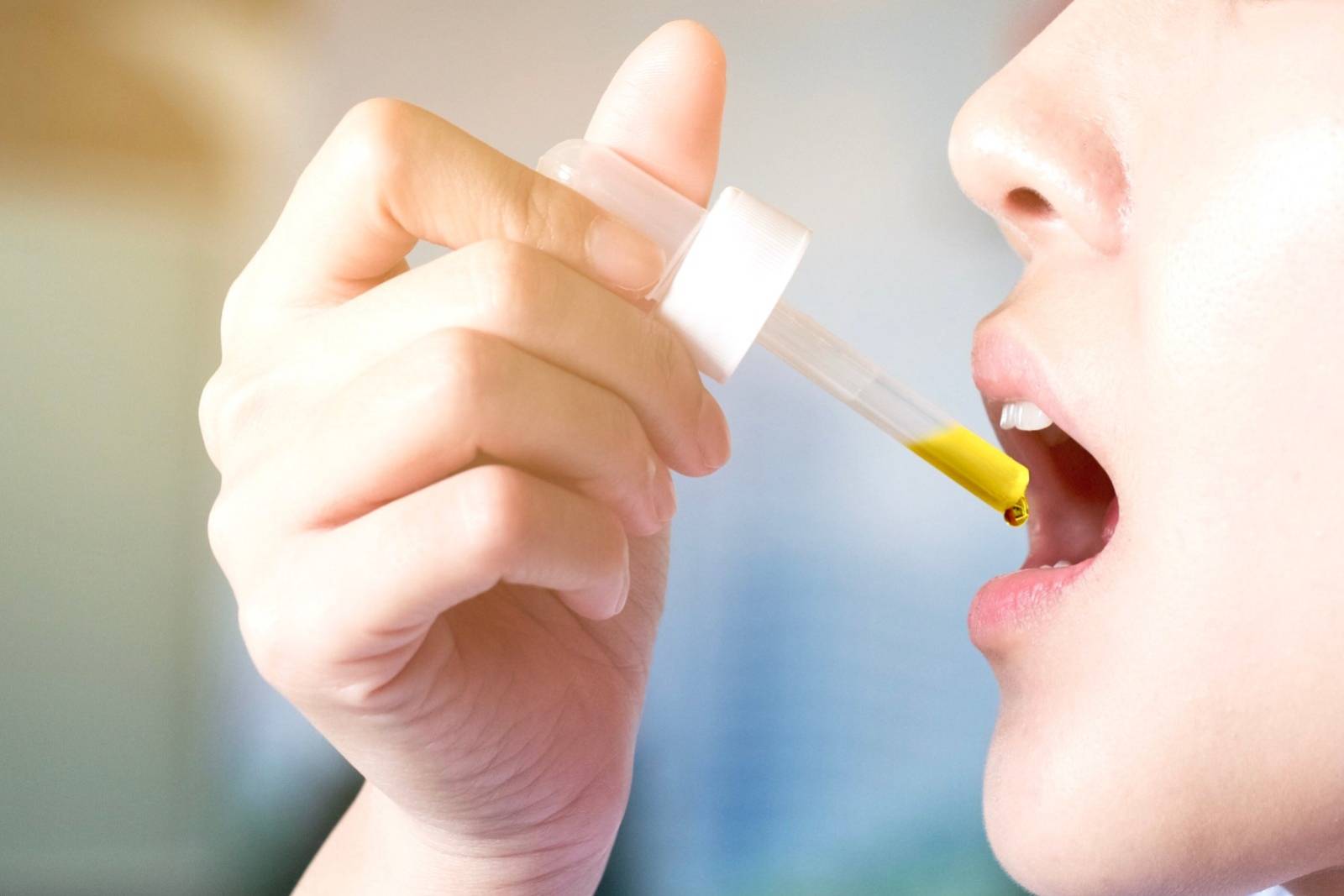 Woman dropping CBD oil under tongue for medical treatment. Speed Greens