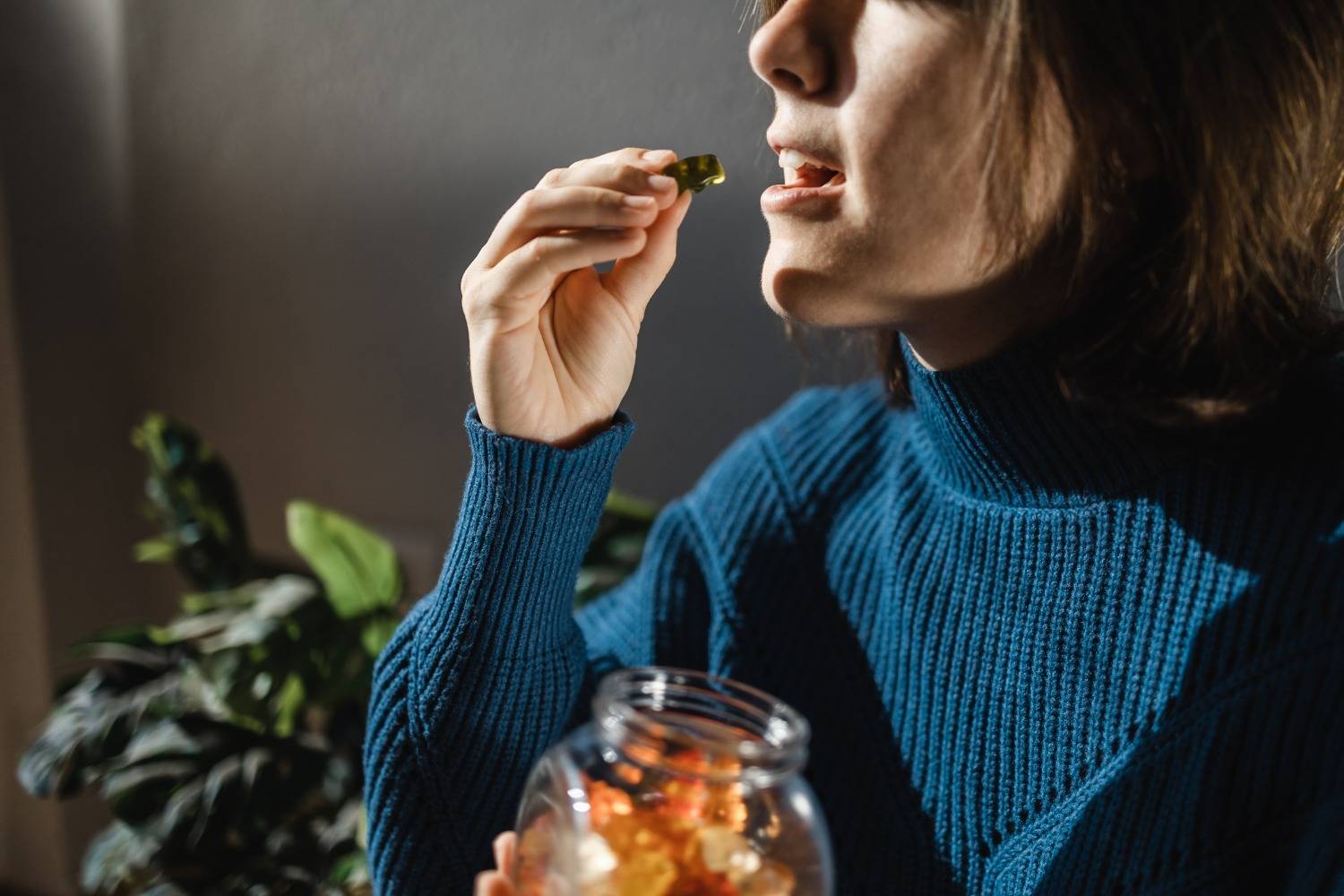 Woman eating cannabis edibles candy from jar. Speed Greens