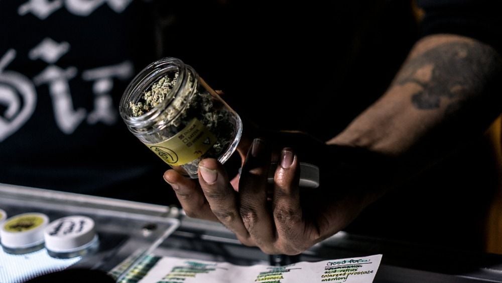 Vendor showing a jar of cannabis. Speed Greens