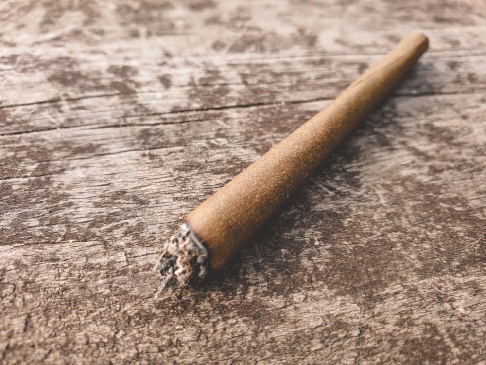 Blunt preroll on a wooden table. Speed greens.